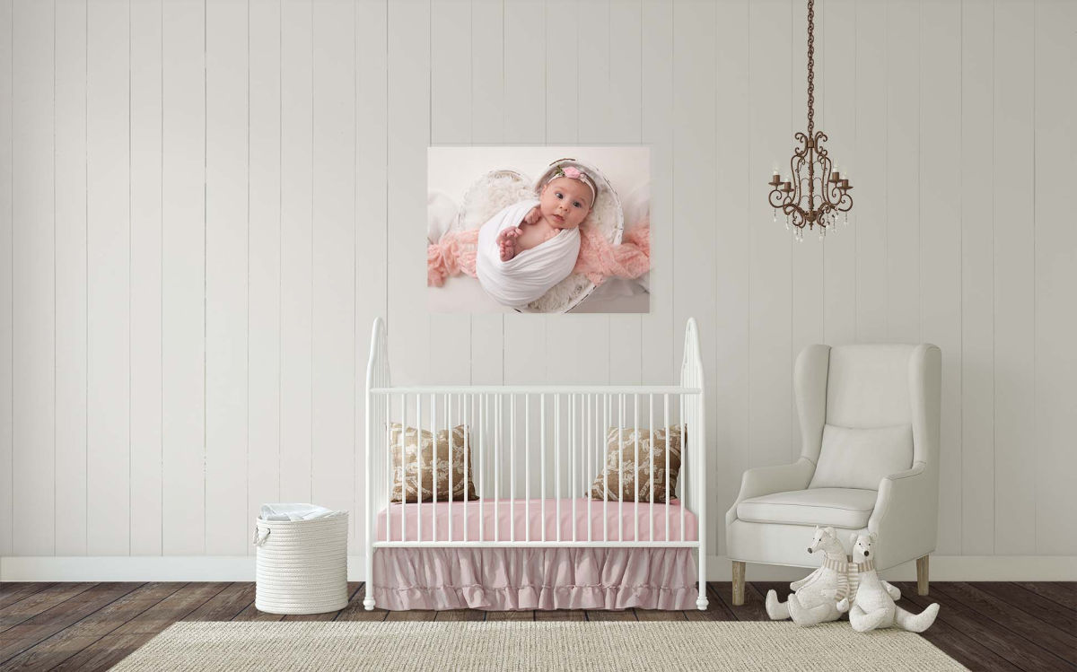 large portrait of newborn above a crib