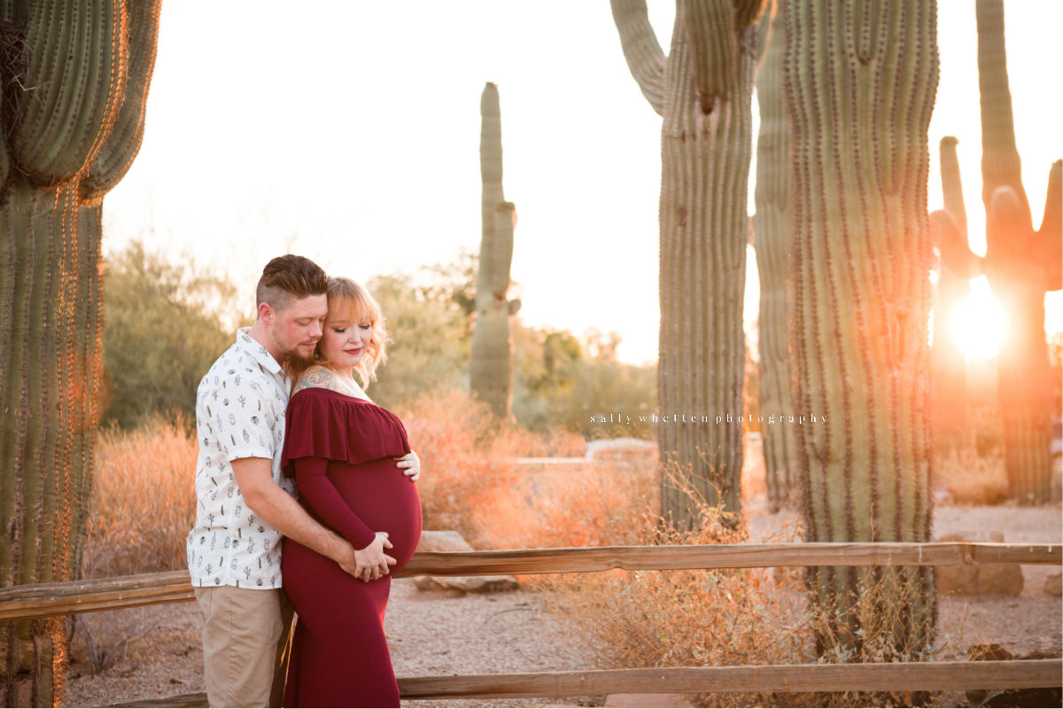 Maternity photo taken at sunset in the Gilbert Riparian Preserve. Pregnant mother with father behind her.