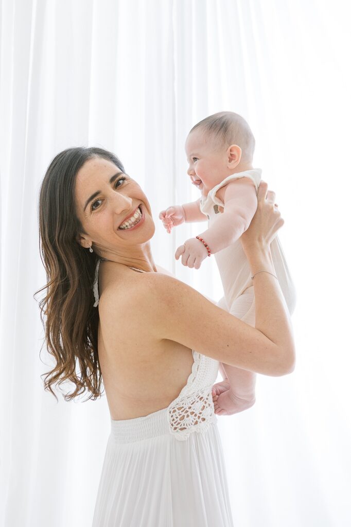 mother holding 5 month old baby boy in the air in scottsdale photo studio