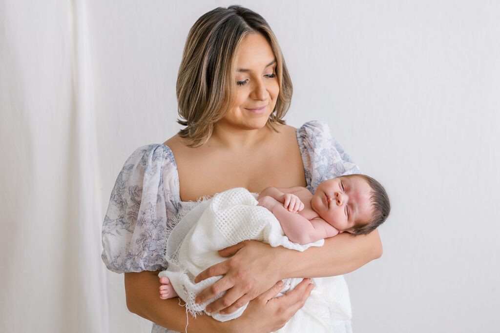 mom cradling her newborn son in her arms in sally whetten photography studio
