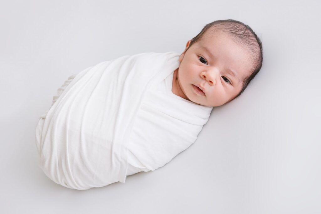 newborn baby boy wrapped in a white swaddle