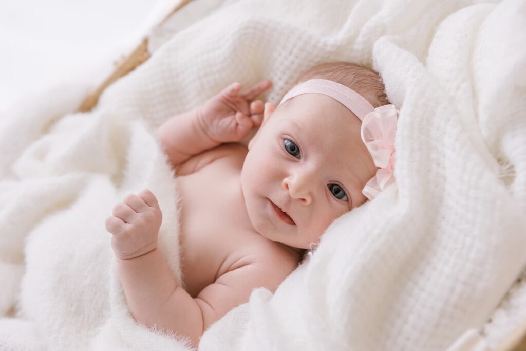 Newborn baby lying on a white blanket during a newborn photo session