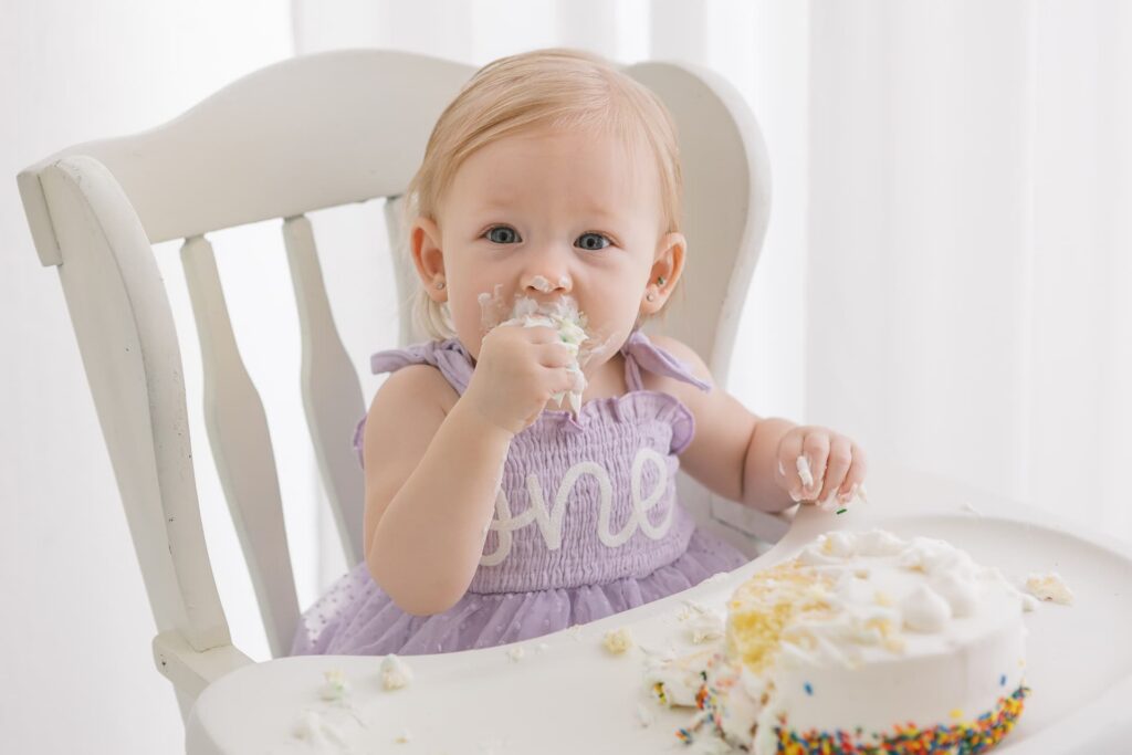 One-year-old baby enjoying her birthday cake during a first birthday photo session