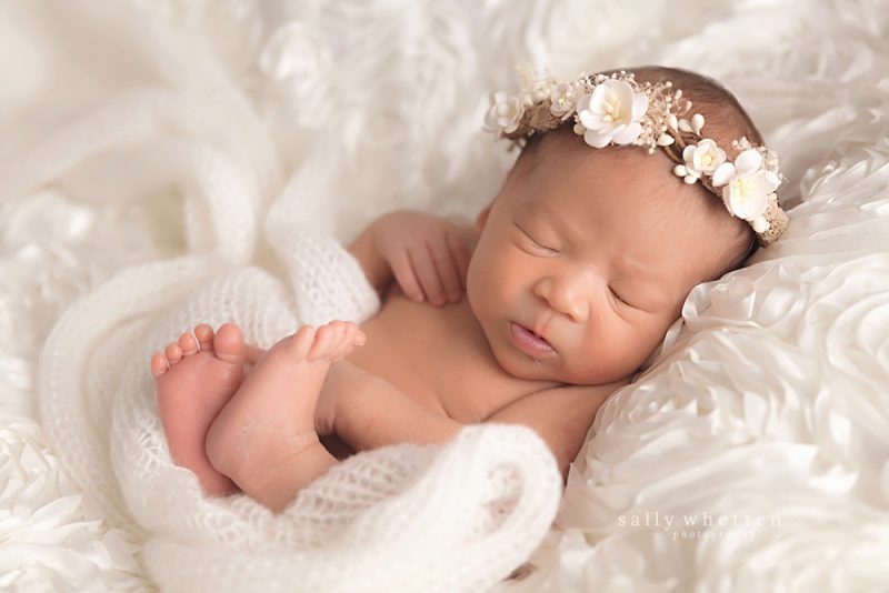 newborn asian baby girl on white blanket with white flower crown