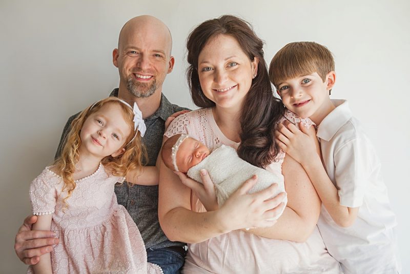 Family of five with newborn baby girl in studio with white background