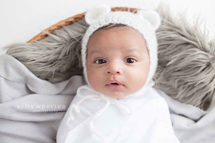 newborn african american boy with white teddy bear hat