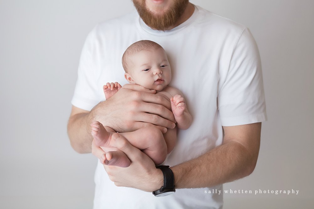 young father in white t shirt holding newborn baby
