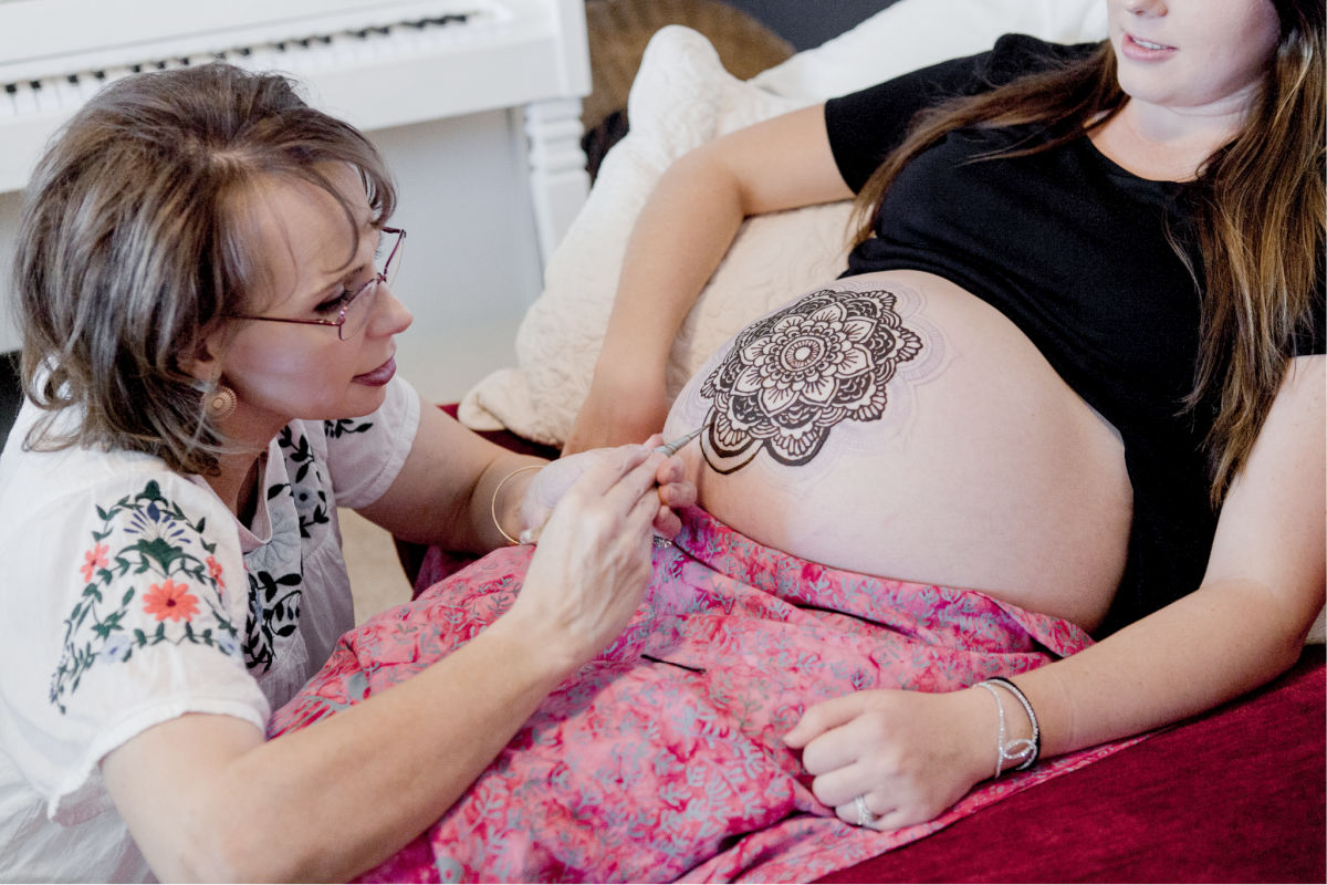 doula painting henna mandala on pregnant belly
