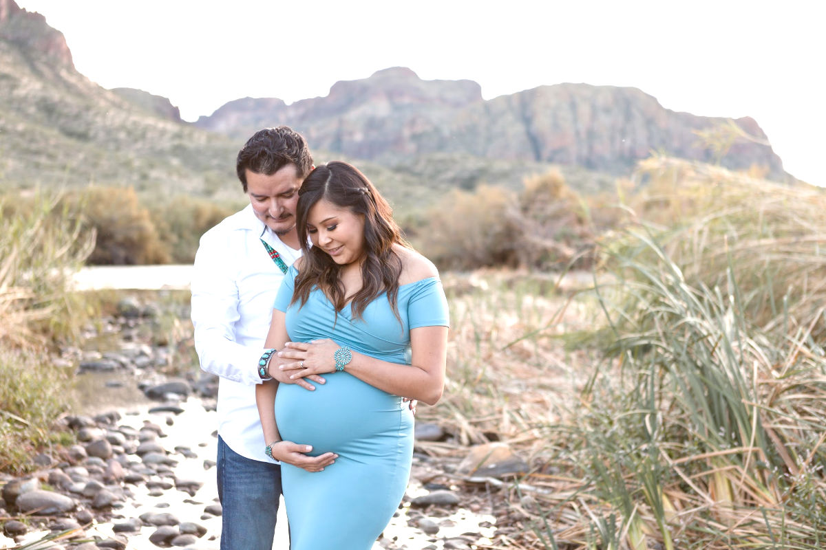 expecting parents looking at pregnant belly by the salt river for a maternity photo shoot