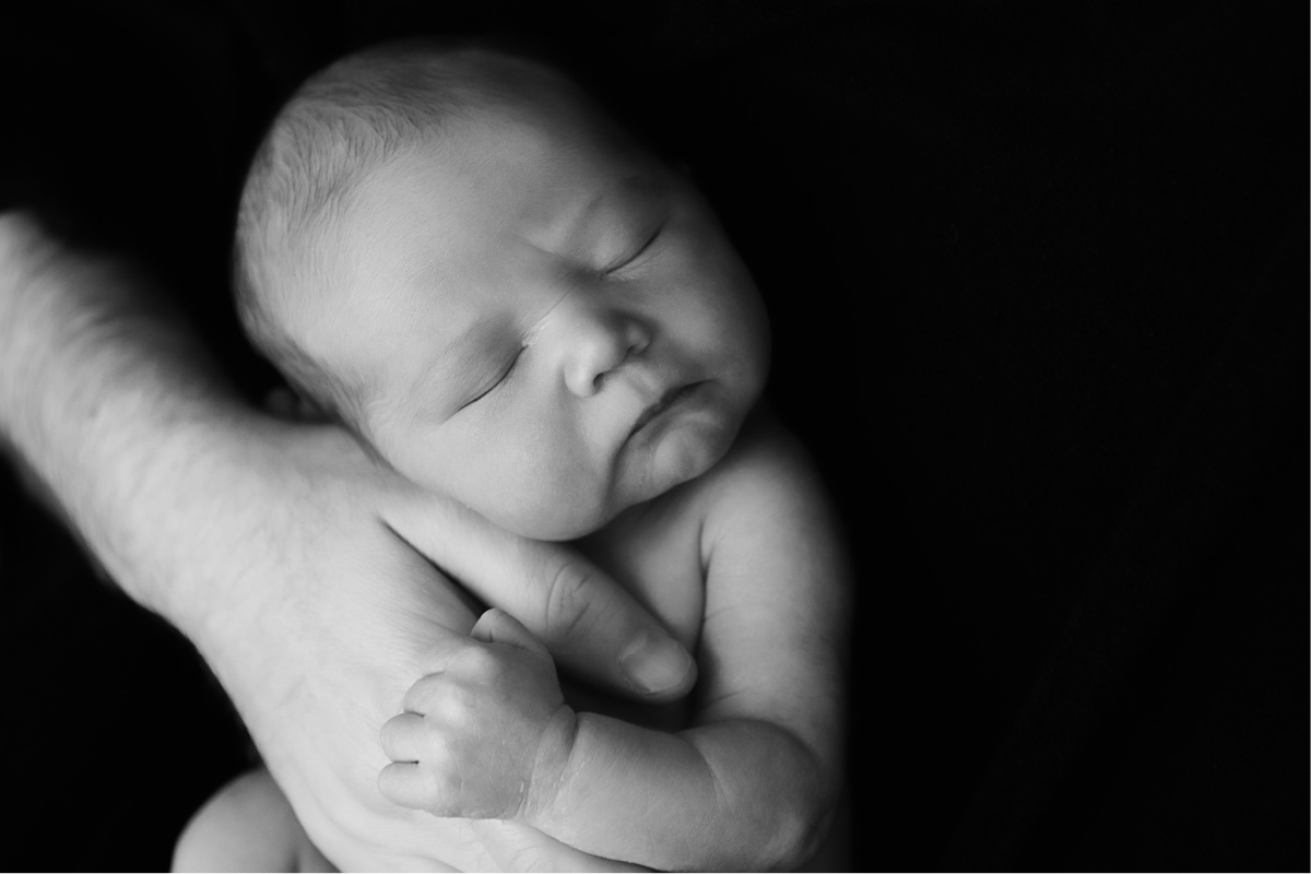 black and white picture of tiny baby boy in his daddy's hands