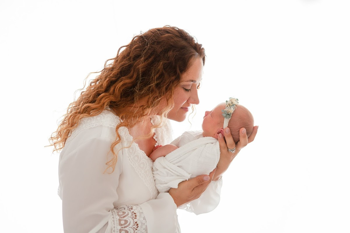 Mother holding newborn baby girl in studio newborn session