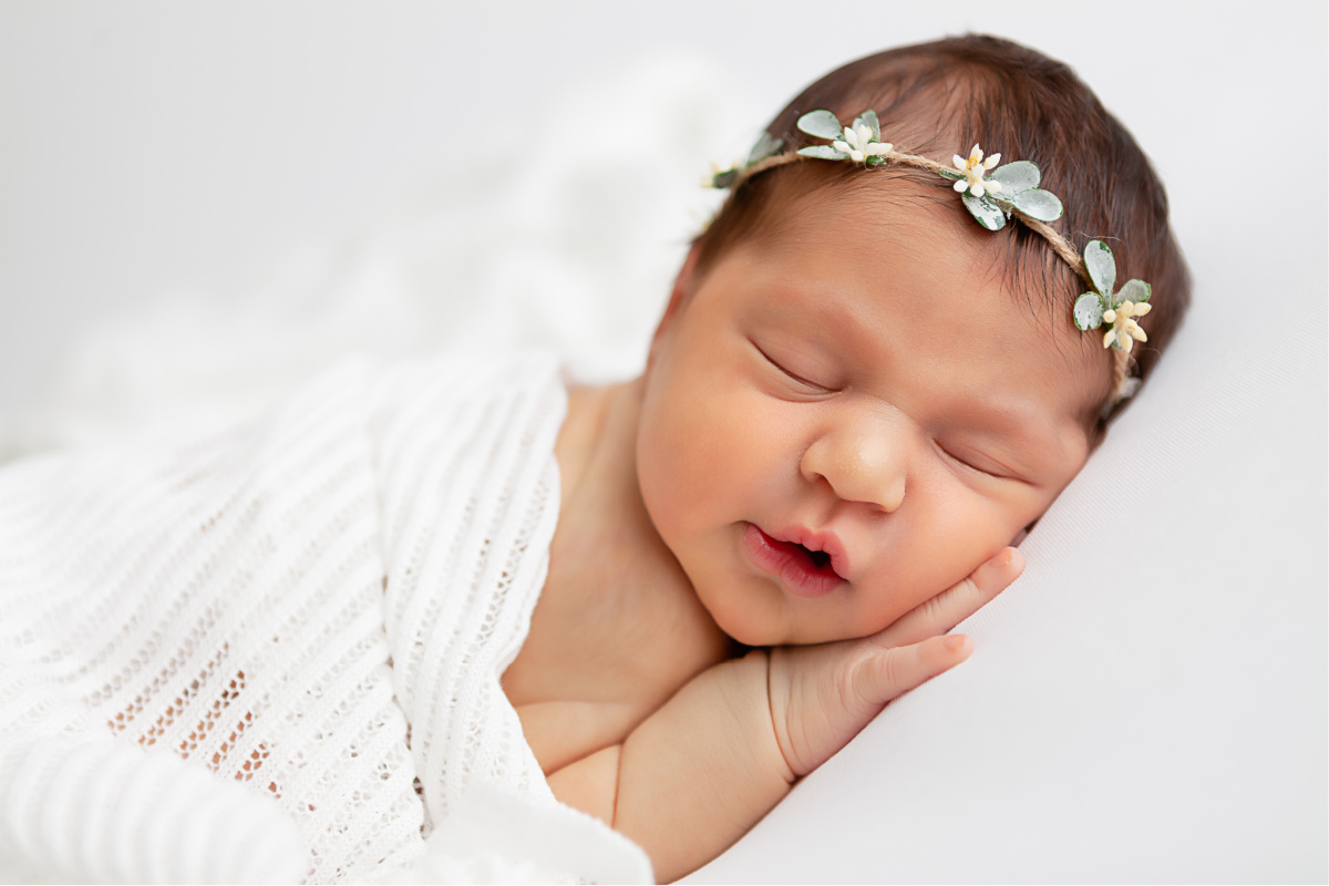 baby girl sleeping on white backdrop with flower crown