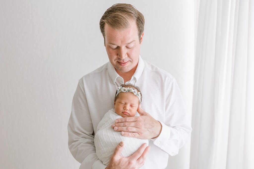 Tender moment of dad holding his newborn daughter in a bright and cozy studio