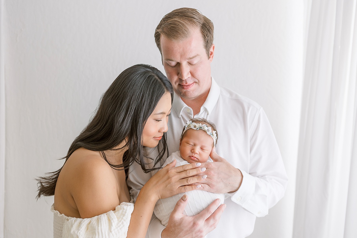Candid moment of mom, dad, and baby girl sharing smiles during a cozy family session with the best newborn photographer Scottsdale.