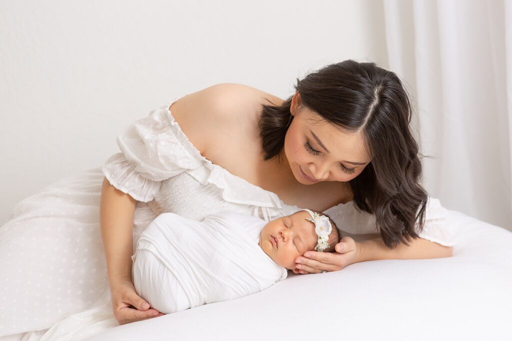 Phoenix baby photographer captures tender moment between mother and baby laying on a white blanket.
