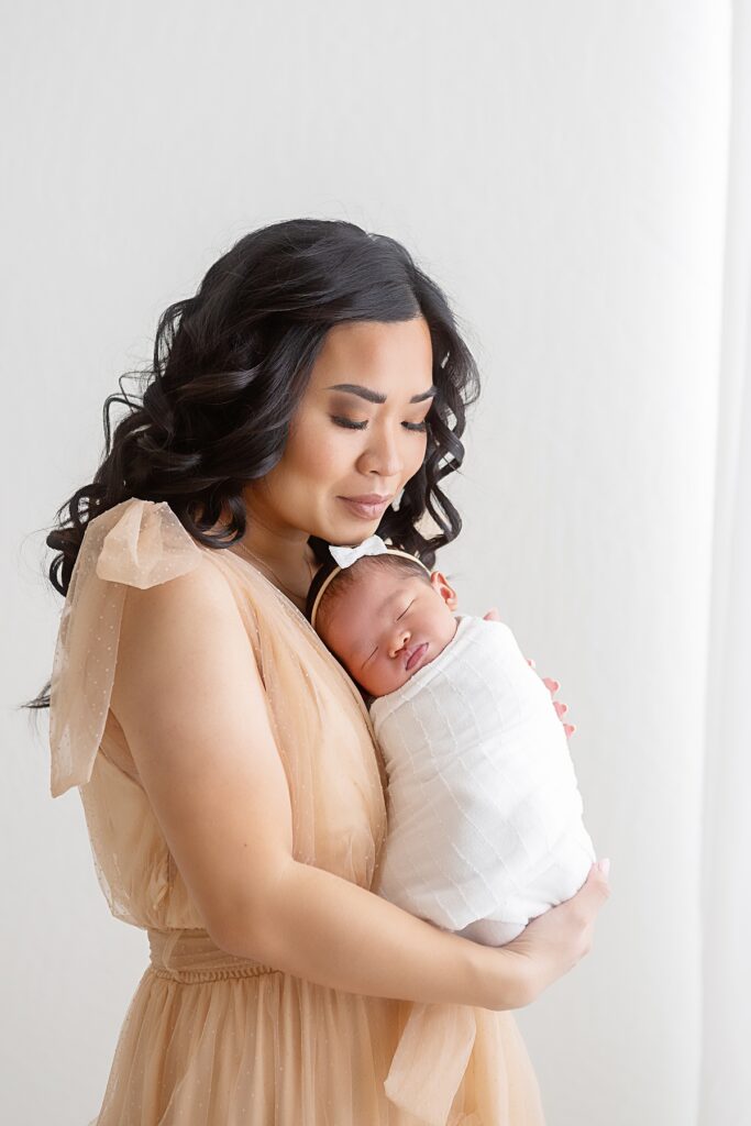 Mother cradling her baby in soft light during a peaceful Scottsdale newborn session with mom