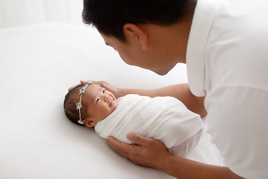 Father holding newborn baby girl during professional photo session