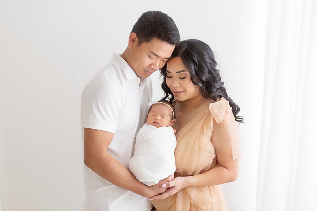 Tender family portrait with parents cuddling their newborn baby girl