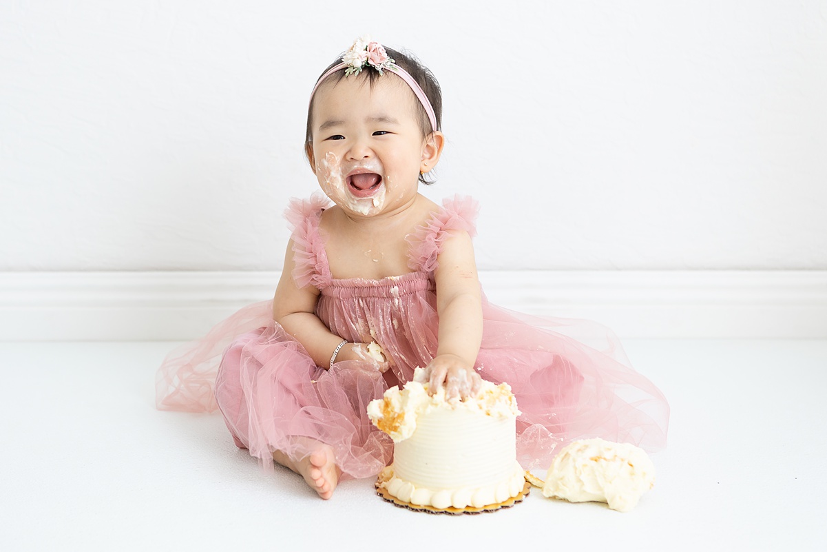 One-year-old girl smiling during a cake smash session in Mesa, AZ studio