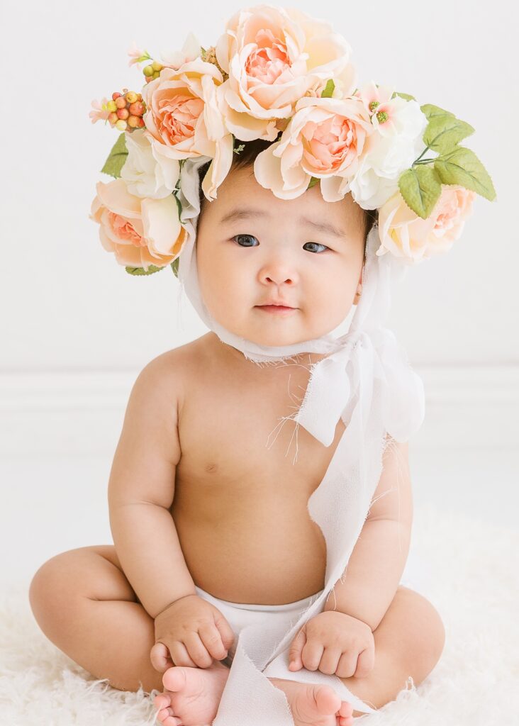 Baby girl wearing floral bonnet during Mesa, AZ studio sitter photo session