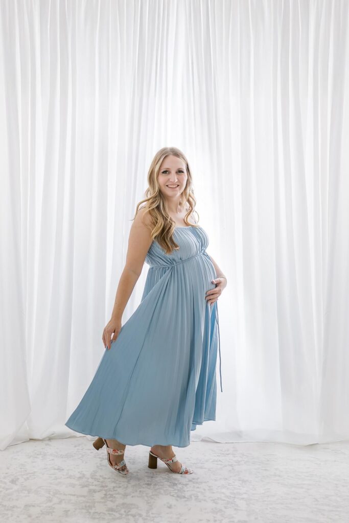 Pregnant mom in a flowing blue dress during a bright white studio maternity session by Gilbert Maternity Photographer Sally Whetten Photography.