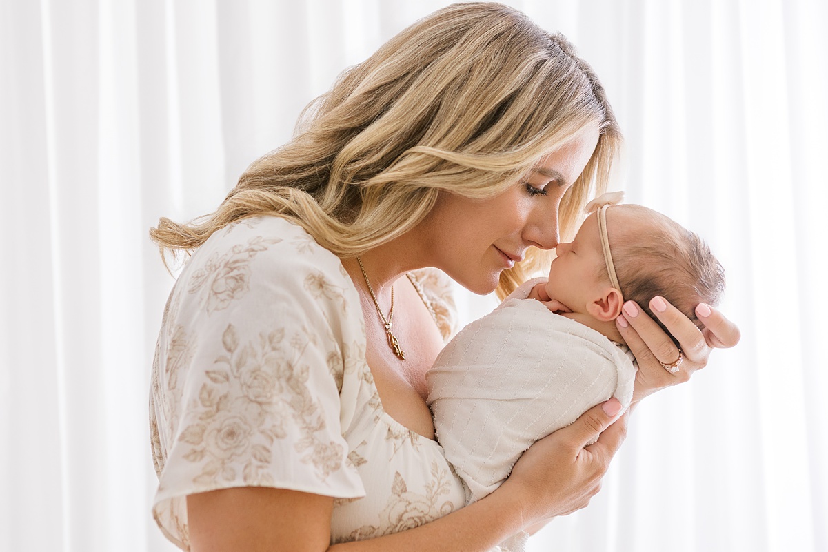 mother and newborn baby girl nose to nose in soft white light studio in scottsdale