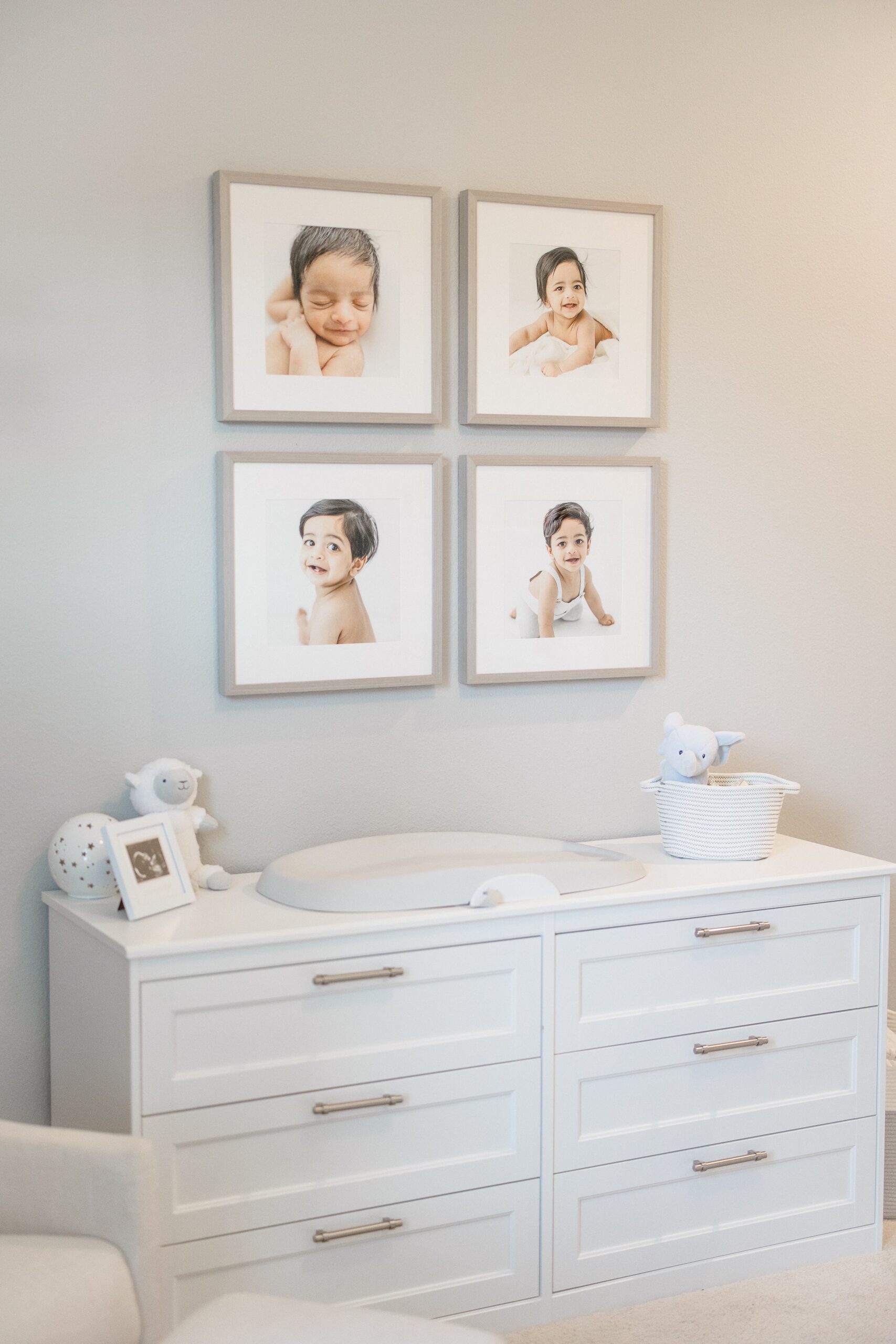 four portraits on the wall in a baby nursery showing the baby as a newborn, 5 month, 9 month and one year.